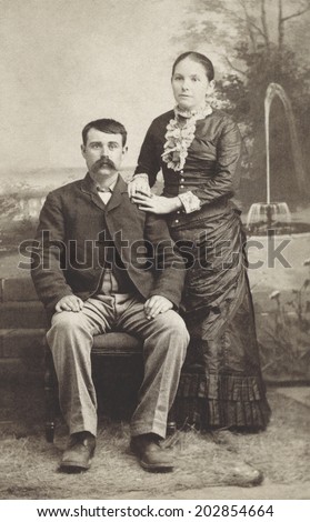 USA - MICHIGAN - CIRCA 1880 Vintage Carte de Viste photo of young couple. The gentleman is sitting and the lady is standing dressed in a Victorian style dress. Photo from Victorian era. CIRCA 1880