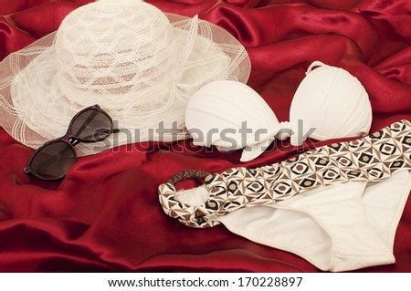 Beach essentials, accessories on a red satin sheet