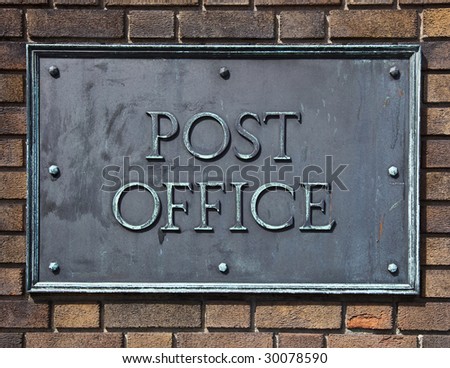 Post office sign made of brass and bolted on a brick wall