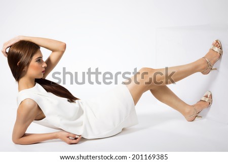 beautiful Indian fashion model sitting on the floor and posing, Indian fashion model wearing white outfit and posing for camera.