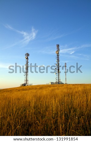 communication towers on top of hill with blue sky background