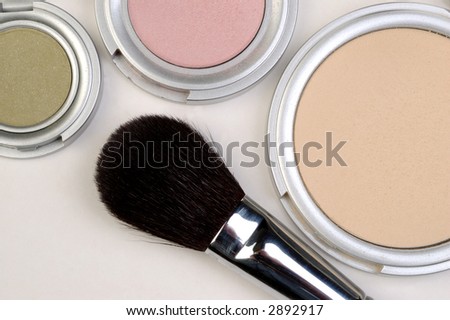 Closeup of a makeup brush and three colors of blush