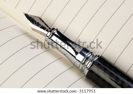 Close-up of a fountain pen with pages of a journal in the background