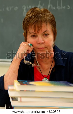 Portrait of a female college professor in a classroom with books in front of her