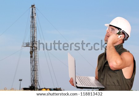 oil worker with laptop and rig