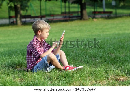 boy sitting on grass and play with tablet pc