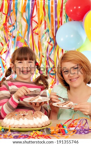 happy mother and daughter eat birthday cake