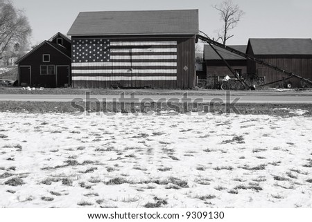 B&W winter view of  barn with American Flag painted on the front.