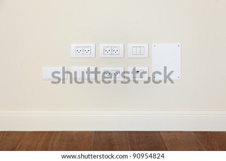 Empty wall with wooden floor. On the wall power outlet and  light switch