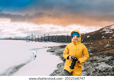 Foto Bild Aurlandsfjellet, Norwegen. Happy Young Woman Tourist Traveler Photographer With Camera Walking Near Aurlandsfjellet Scenic Route Road. Aktiver Lebensstil in der norwegischen Natur