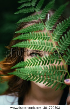 Close Up Portrait Of a Smiling Young Happy Beauty Red Hair Girl Holding Leaf Up To Face In Summer Park Forest