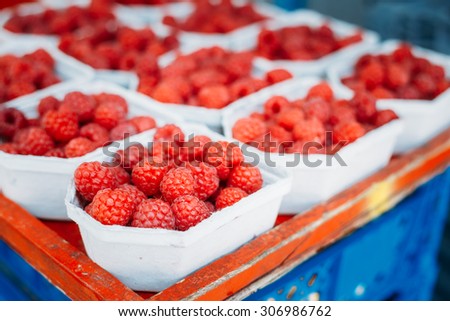 Assortment Of Fresh Organic Red Berries Raspberries At Produce Local Market In Baskets, Containers.