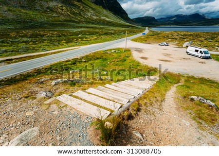 Asphalt country road in the mountains in Norway. Cars are on the side of a asphalt country road against Background Of The Norwegian Mountain Landscape. Norway.