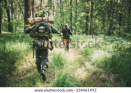Unidentified re-enactors dressed as German soldiers running through summer forest