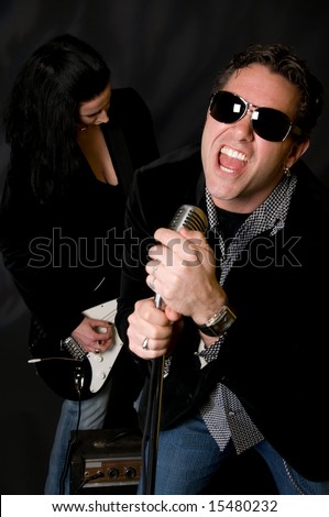 Male lead singer with retro mic and female guitar player in background