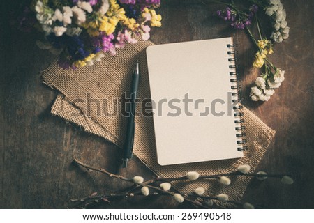 Small notepad with pen and pencil on rustic wood background with film filter effect