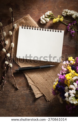 Small notepad with pen and pencil on rustic wood background with film filter effect
