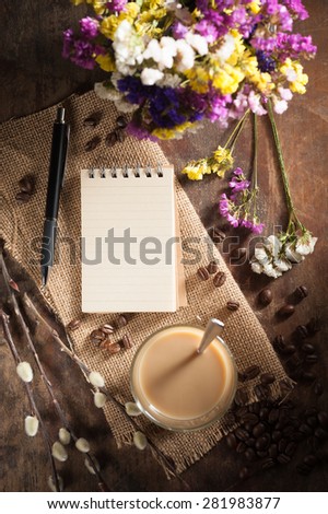 Notepad with pen, a glass of Thai tea on rustic wood background with low key scene