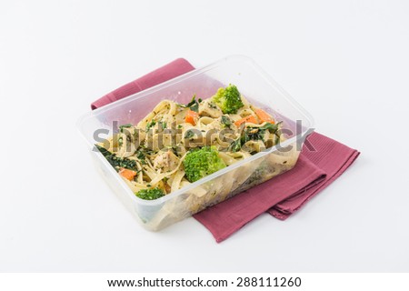 Fettuccine pesto sauce with spinach, grilled fish and vegetables cooked by clean food concept in lunch box on white table
