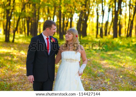 couple at the wedding are the yellow autumn forest, the groom looks at his bride