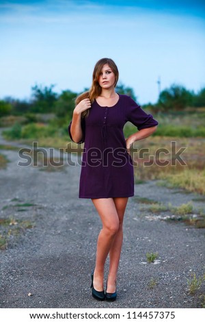 young woman knitted model portrait dress of purple on blue background with natural breasts and shoulders bare feet