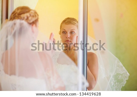 sunlight bride looks in the mirror in the wedding day