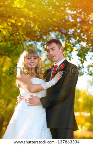 couple wedding sunlight yellow autumn forest, the groom looks at his bride