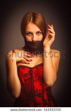 woman girl in a red corset, her mouth covered with a bandage, a symbol of silence and stillness, unusual art photo
