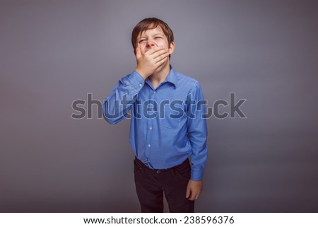 teenager boy 10 years of European appearance brown hair yawns covered his mouth with his hand experience fatigue