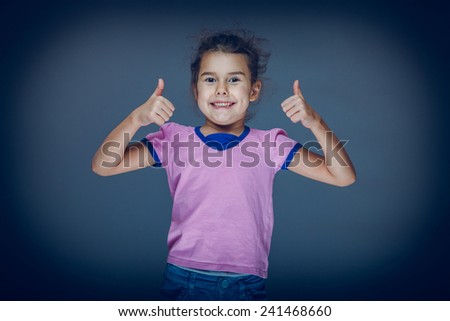 Teen girl shows gesture so hands on a gray background cross process