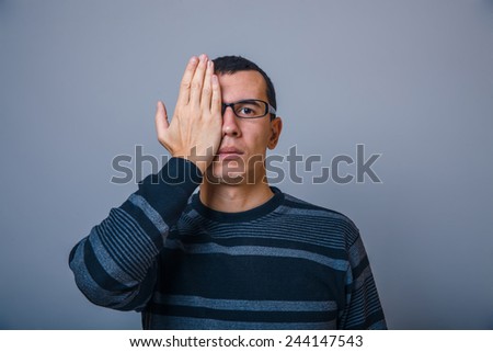 European-looking man of 30 years with glasses, put his hand over eye