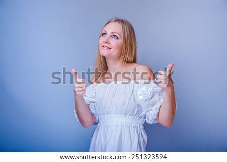 European-looking woman of thirty years thumbs up gesture yes on a gray background