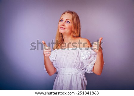 European-looking woman of thirty years thumbs up gesture yes on a gray background retro