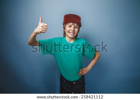 boy teenager European appearance in a green t-shirt showing OK sign on a gray background, a Muslim