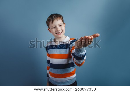 European-looking boy of ten  years pulls his hand requests on a gray background