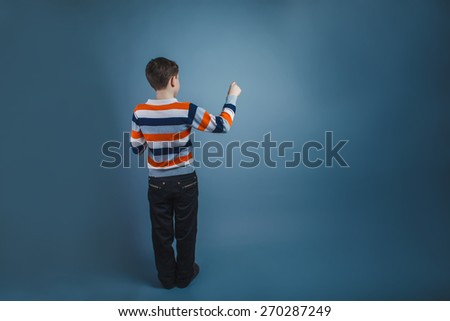teenager boy of about ten European appearance Brown turned his back writes on a gray  background