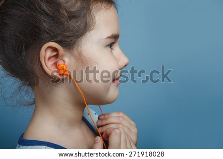 Girl European appearance five years listening to music with headphones on a  gray  background