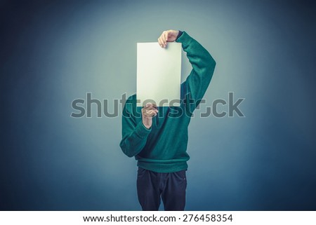 European-looking boy of ten years covered his face with a clean sheet on a gray background instagram effect style