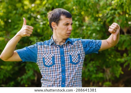 Man outdoors thumbs up thumbs down on a green background leaves summer