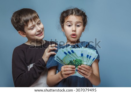 Boy teenager European appearance ten years and Girl European appearance ten years  holding money bills in his  hands on a  gray  background
