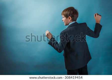 Teen boy clenched his fists fights businessman standing in profile against the background of the photo studio