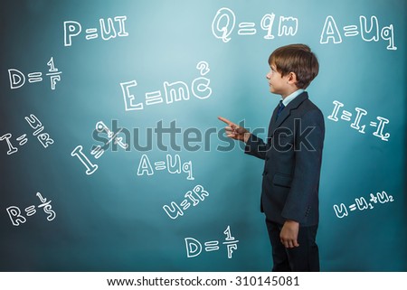 Teen boy genius scientist shows the board with formulas in physics and science teaching studio background