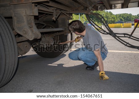 18-Wheeler Pre-trip Tire Inspection - A professional driver is using a tire thumper to check the tires underneath his trailer prior to driving OTR.   Imagine de stoc © 
