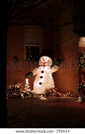 Inflatable snowman stands in the corner with holiday christmas lights.