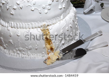 A wedding cake with the first slice cut out by the bride and groom.