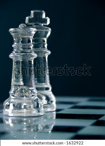 King and queen on the chess board, macro image of glass pieces.  Shallow dof, focus on the queen in front.