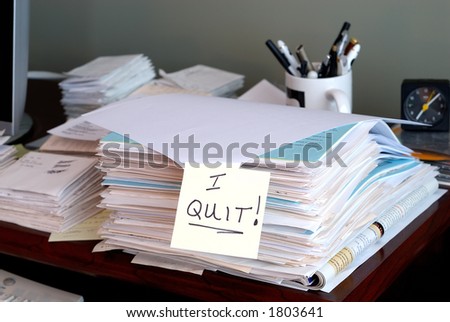 I Quit - A sticky note that says I QUIT on a pile of unfinished work in the office.