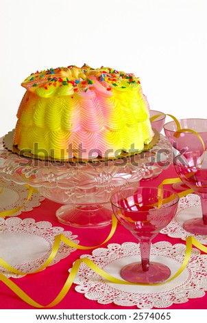 Birthday Cake - A pink and yellow iced birthday cake, yellow ribbons and pink stemware for a birthday party.