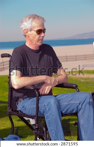 Man sitting in a wheelchair at the beach on a sunny day.