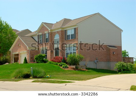 A 2-story brick home in the suburbs in summer time.